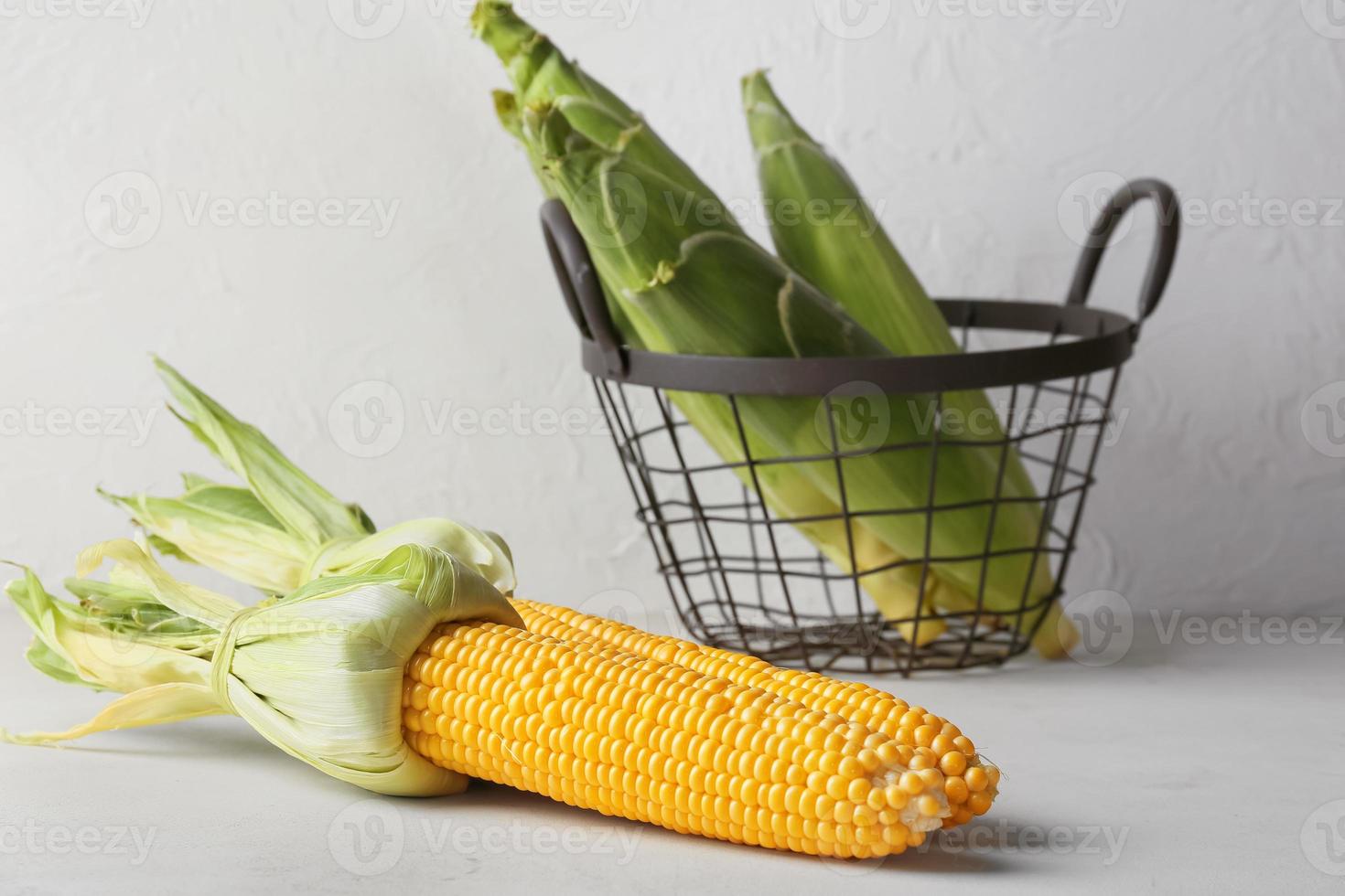 Fresh corn cobs on light background photo