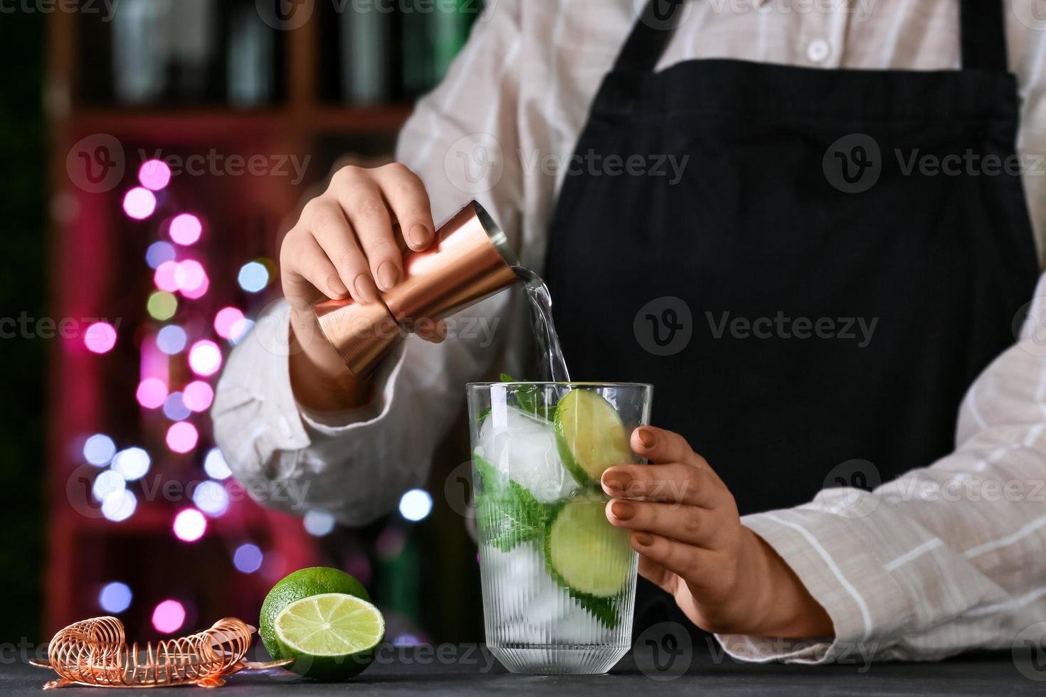 Camarero haciendo mojito fresco en la mesa en el bar foto