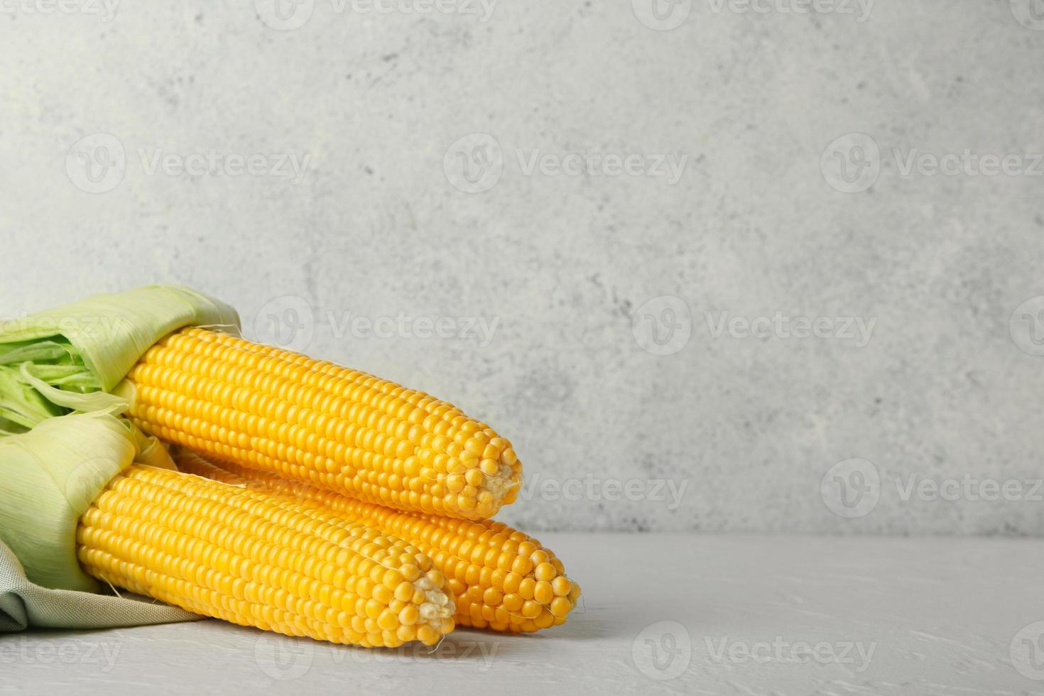 Fresh corn cobs on light background photo