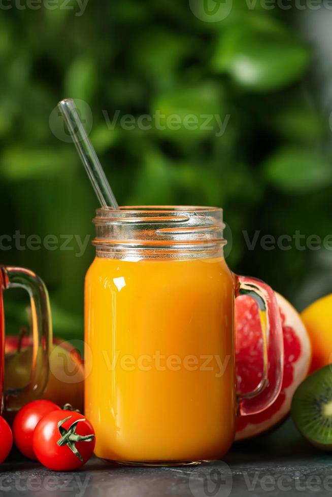 Mason jar with healthy juice, fruits and vegetables on table outdoors, closeup photo