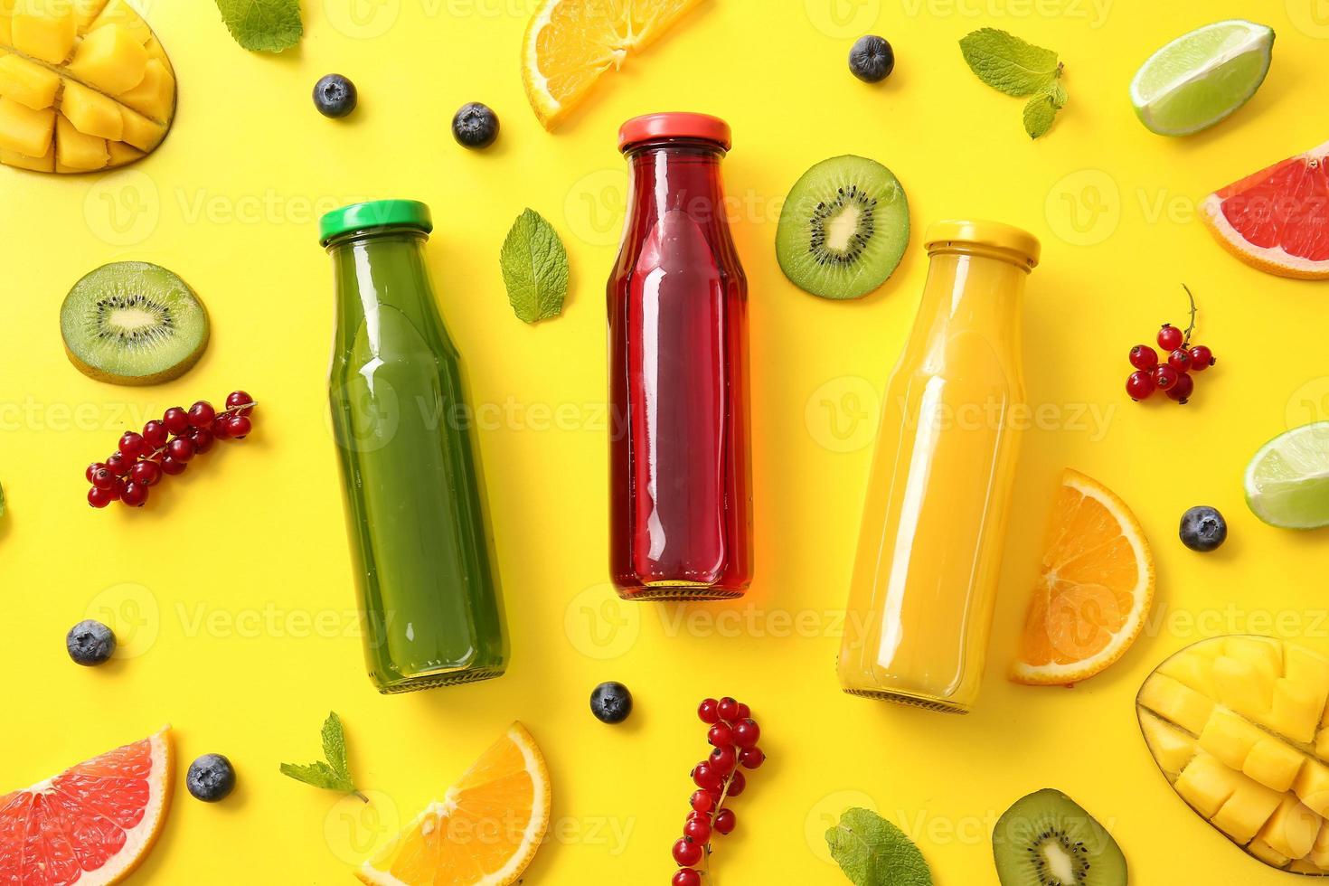 Bottles with healthy juice and fruits on color background photo