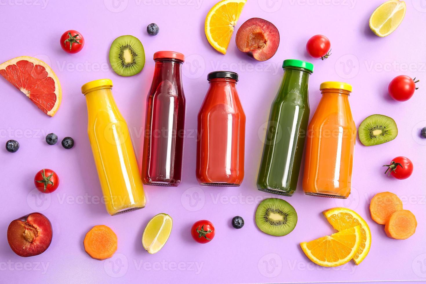 Botellas con jugos saludables, frutas y verduras sobre fondo de color foto