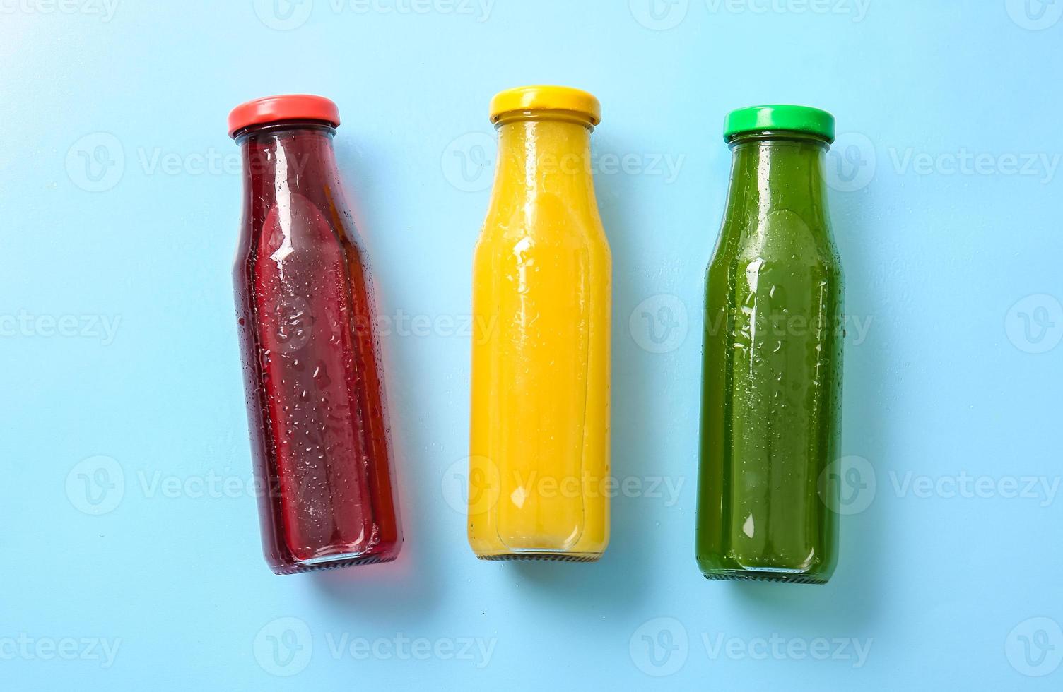 Bottles with healthy juice on color background photo