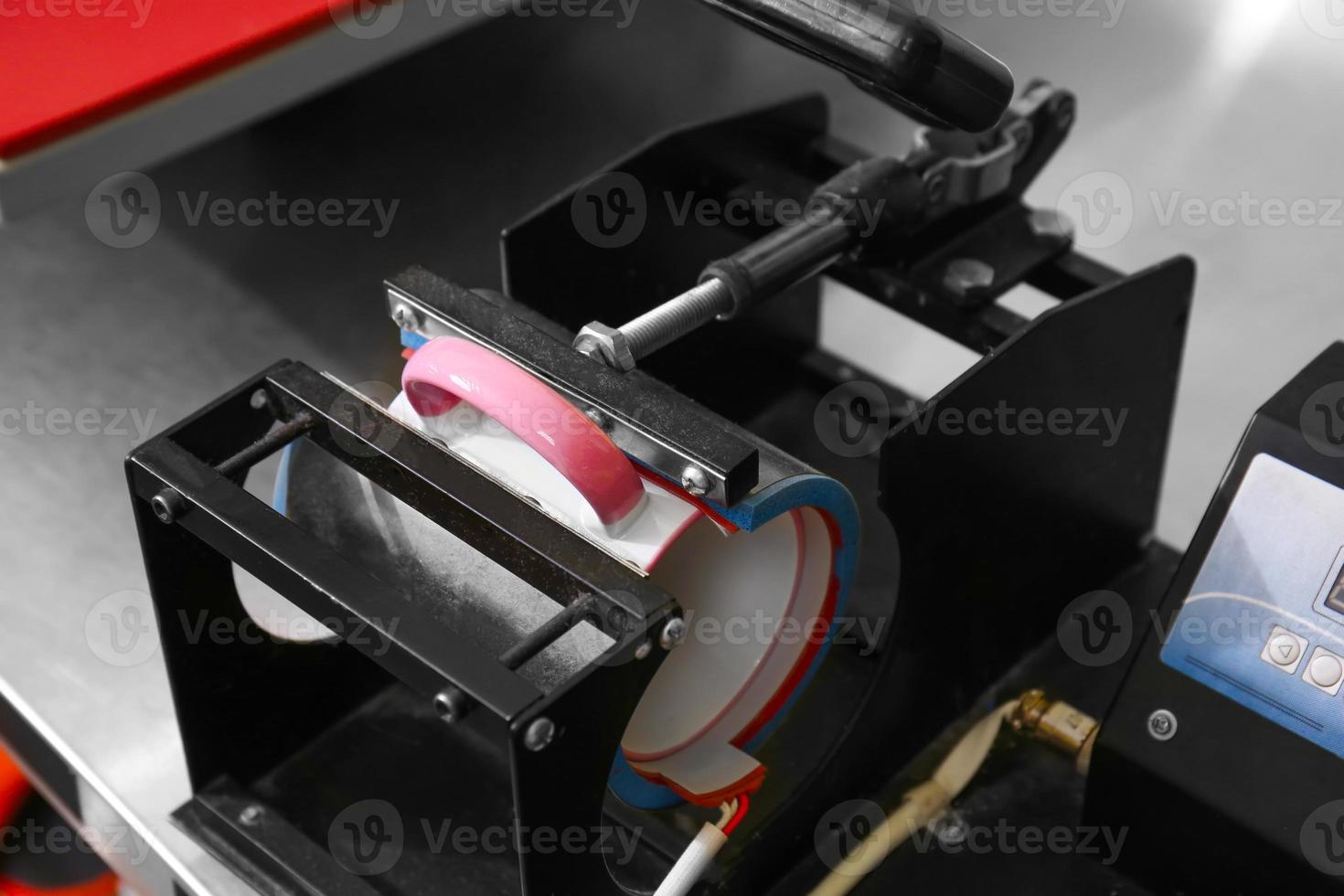 Ceramic cup in printing machine at workshop photo