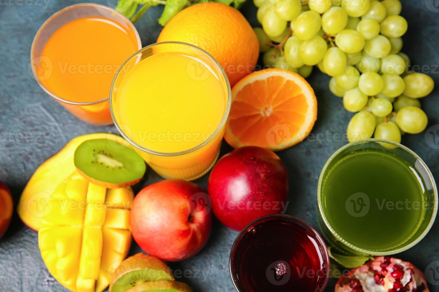 Glasses with healthy juice, fruits and vegetables on dark background photo