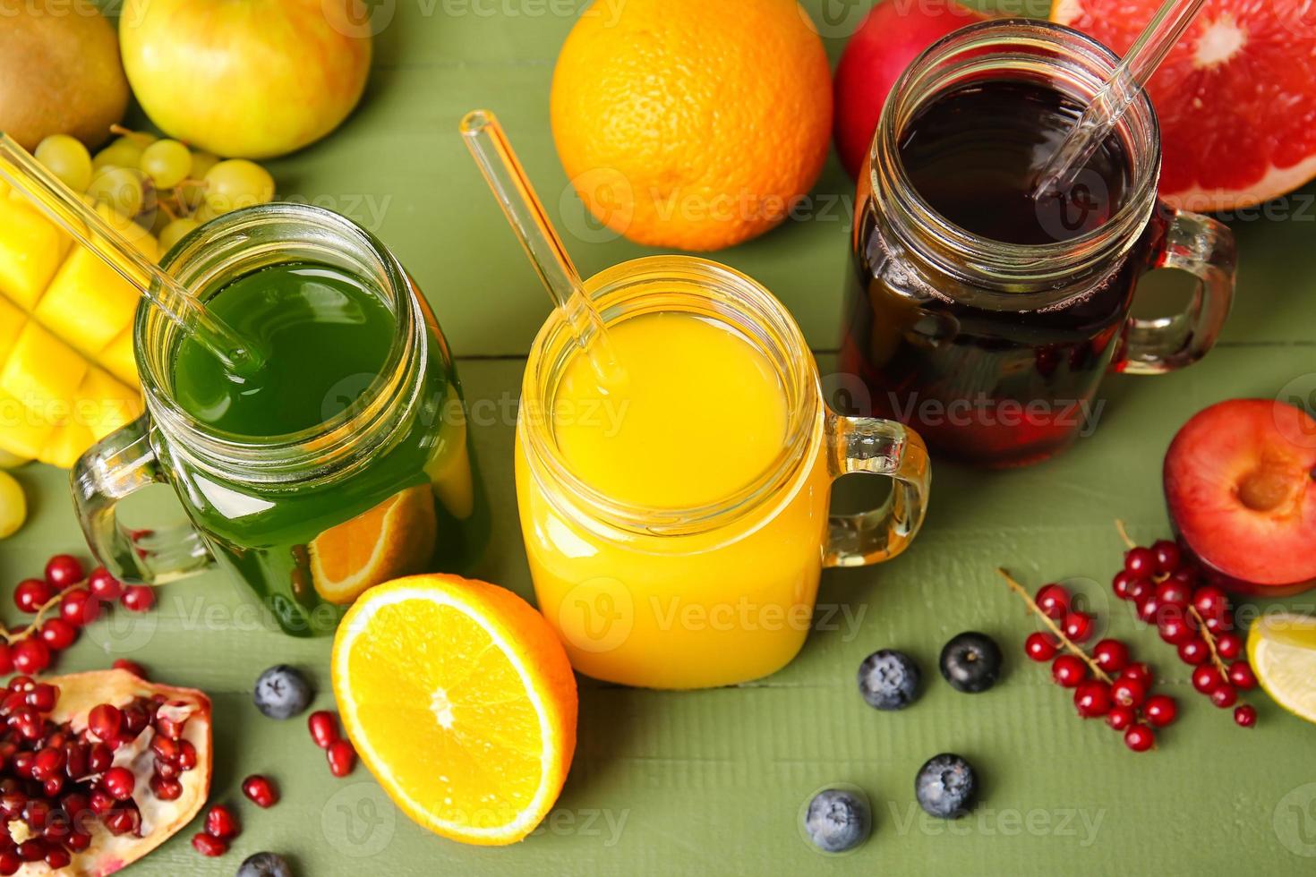 Mason jars with healthy juice, fruits and vegetables on color wooden background photo