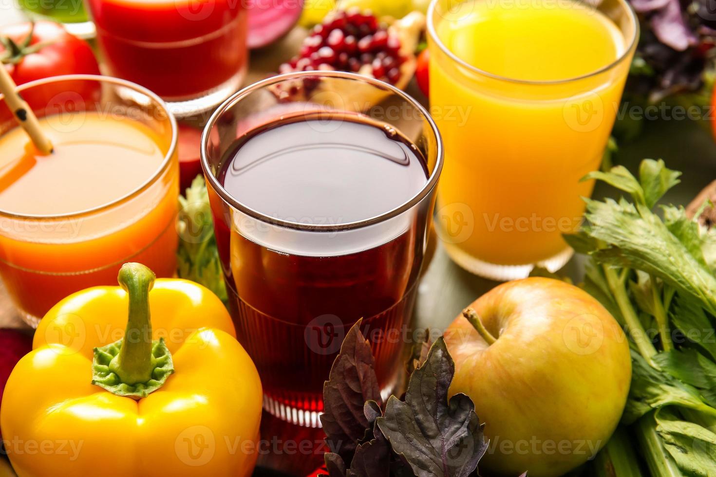 Glasses with healthy juice, fruits and vegetables on color wooden background photo