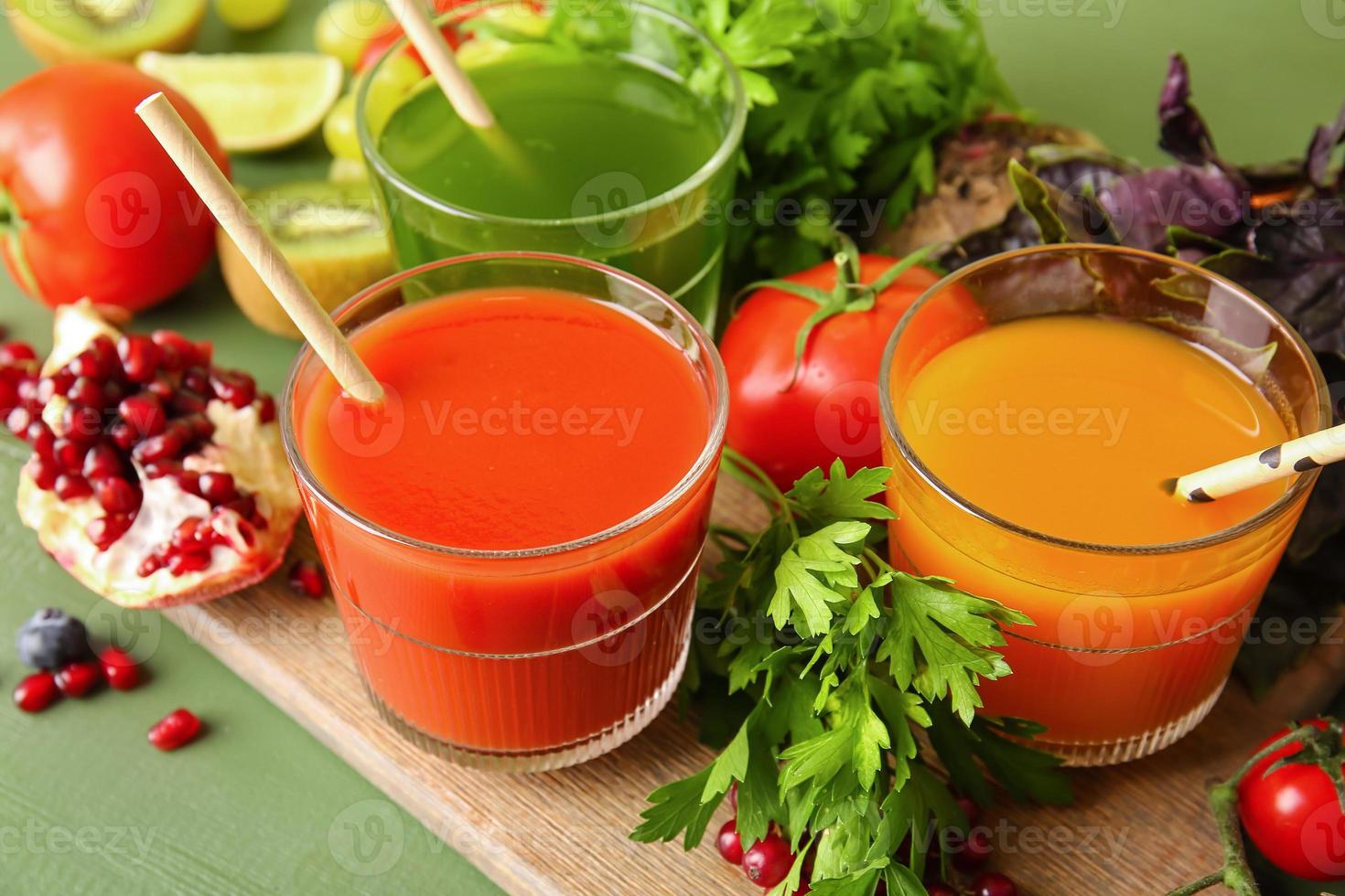 Glasses with healthy juice, fruits and vegetables on color wooden background photo