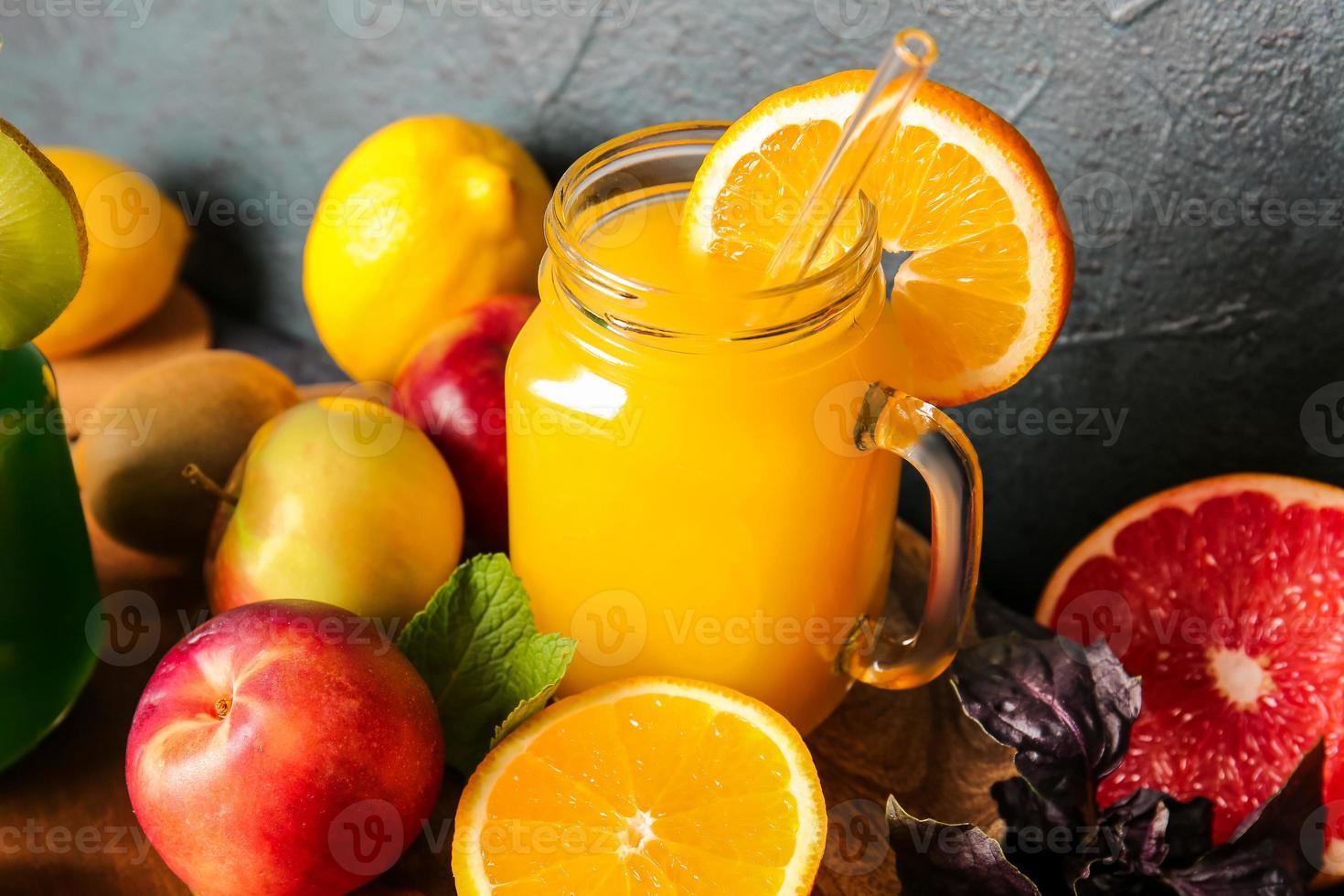 Tarro de albañil con jugos saludables, frutas y verduras sobre fondo oscuro foto