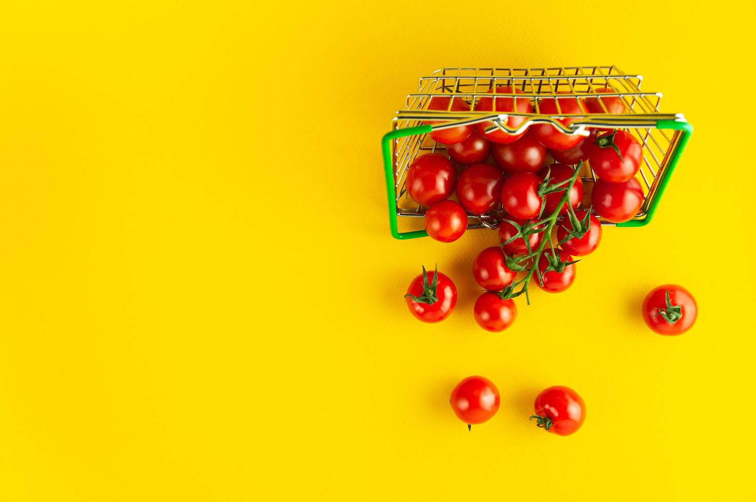 Scattered cherry tomatoes in a basket on a bright yellow background with an empty place for an inscription. photo