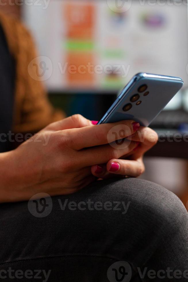 Primer plano de la mano de la empresaria charlando con un amigo mediante un smartphone moderno foto