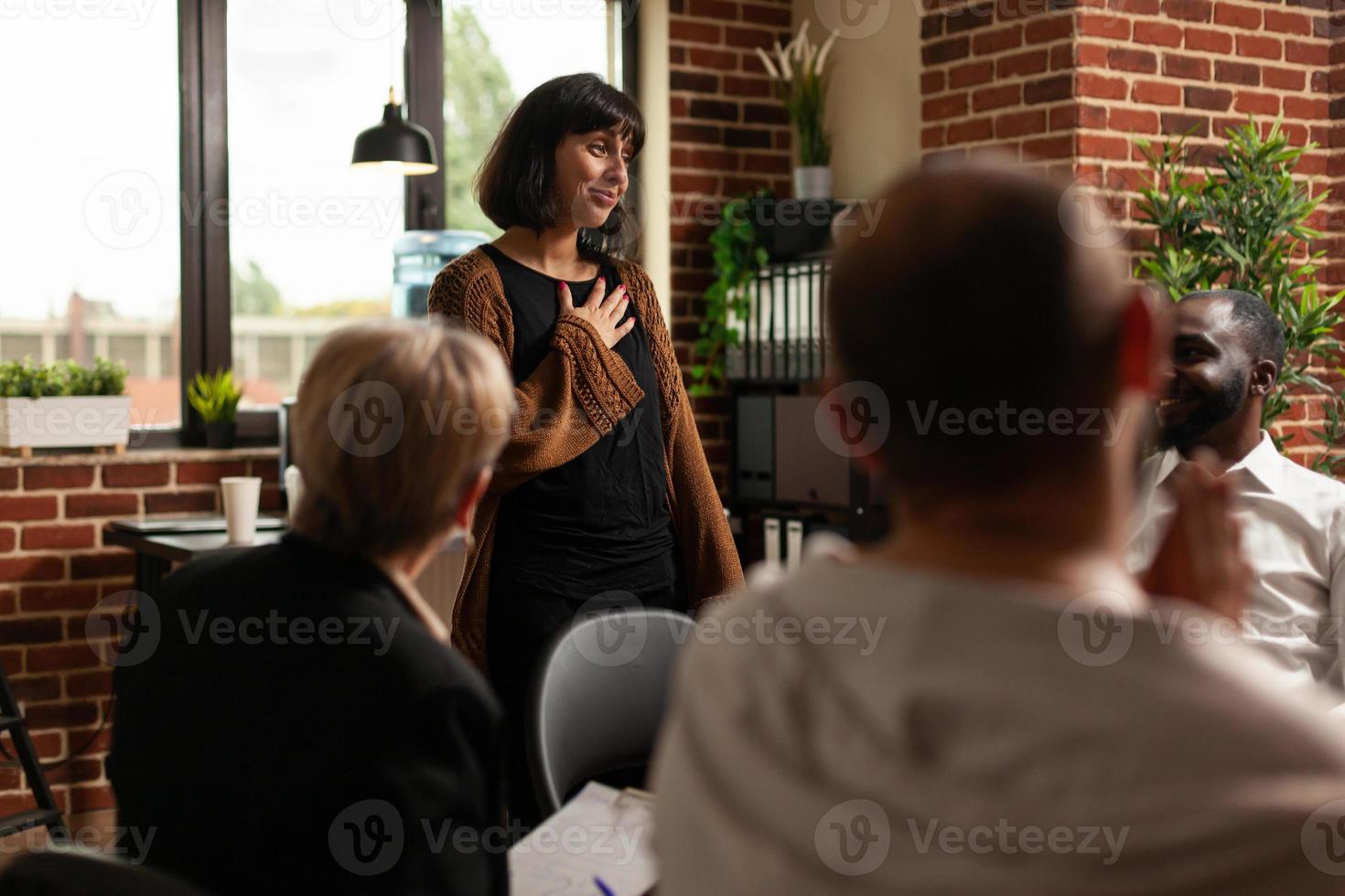 Impressed woman receiving applause from group of people at aa meeting program photo