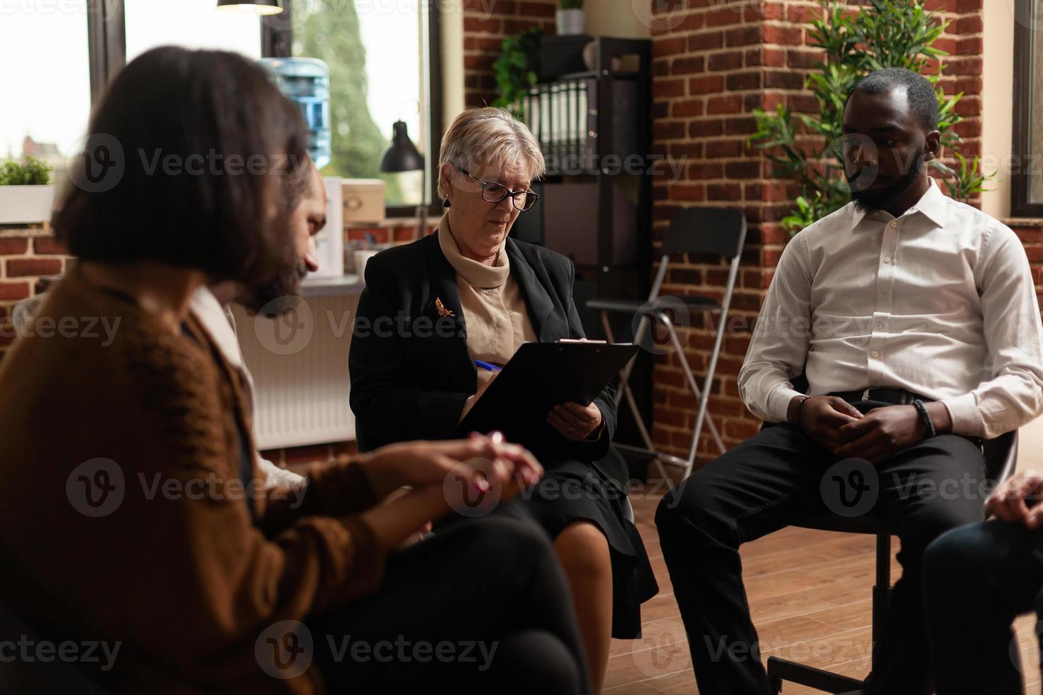 Woman psychologist giving rehab advice to people at aa group therapy session photo