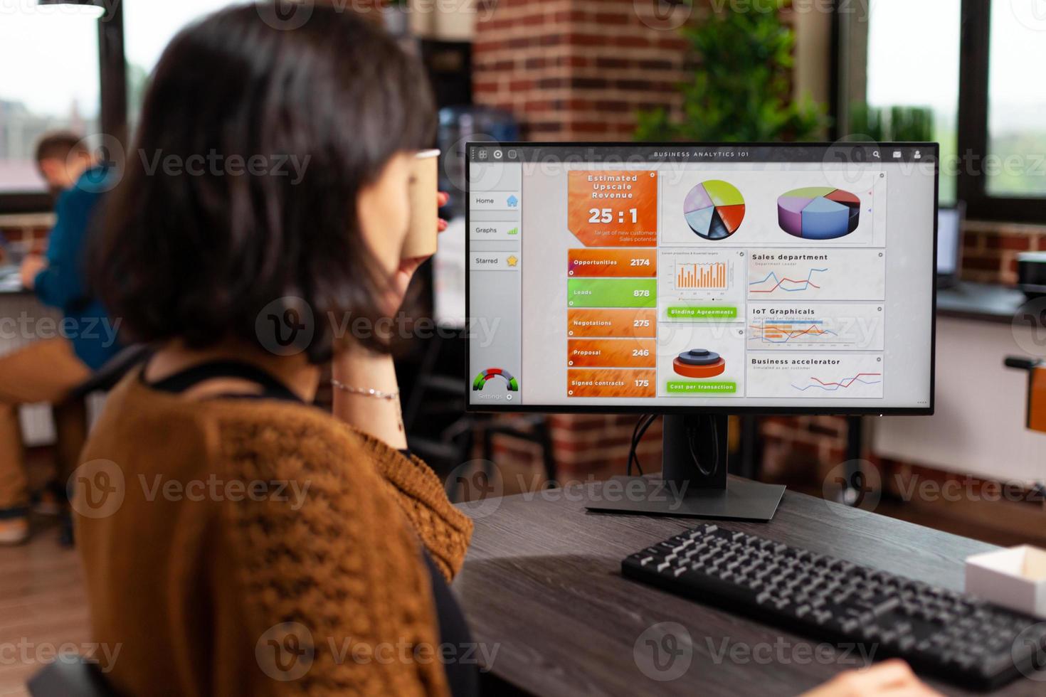 Mujer emprendedora sosteniendo una taza de café analizando los gráficos de la empresa escribiendo estrategia de gestión foto