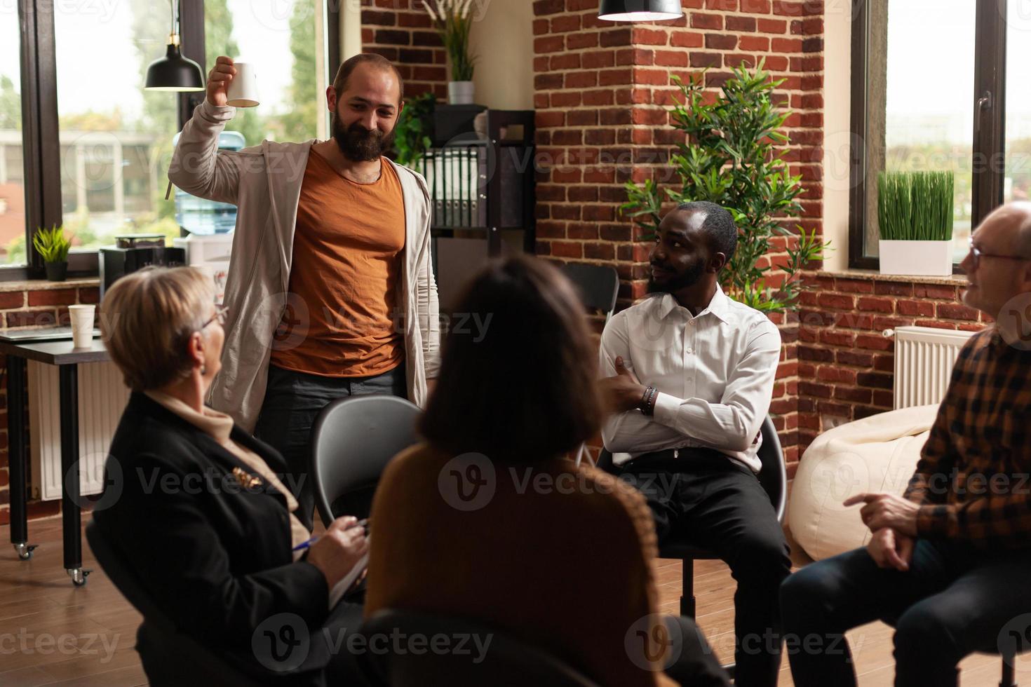 Hombre hablando de logros con personas en una sesión de reunión de grupo foto