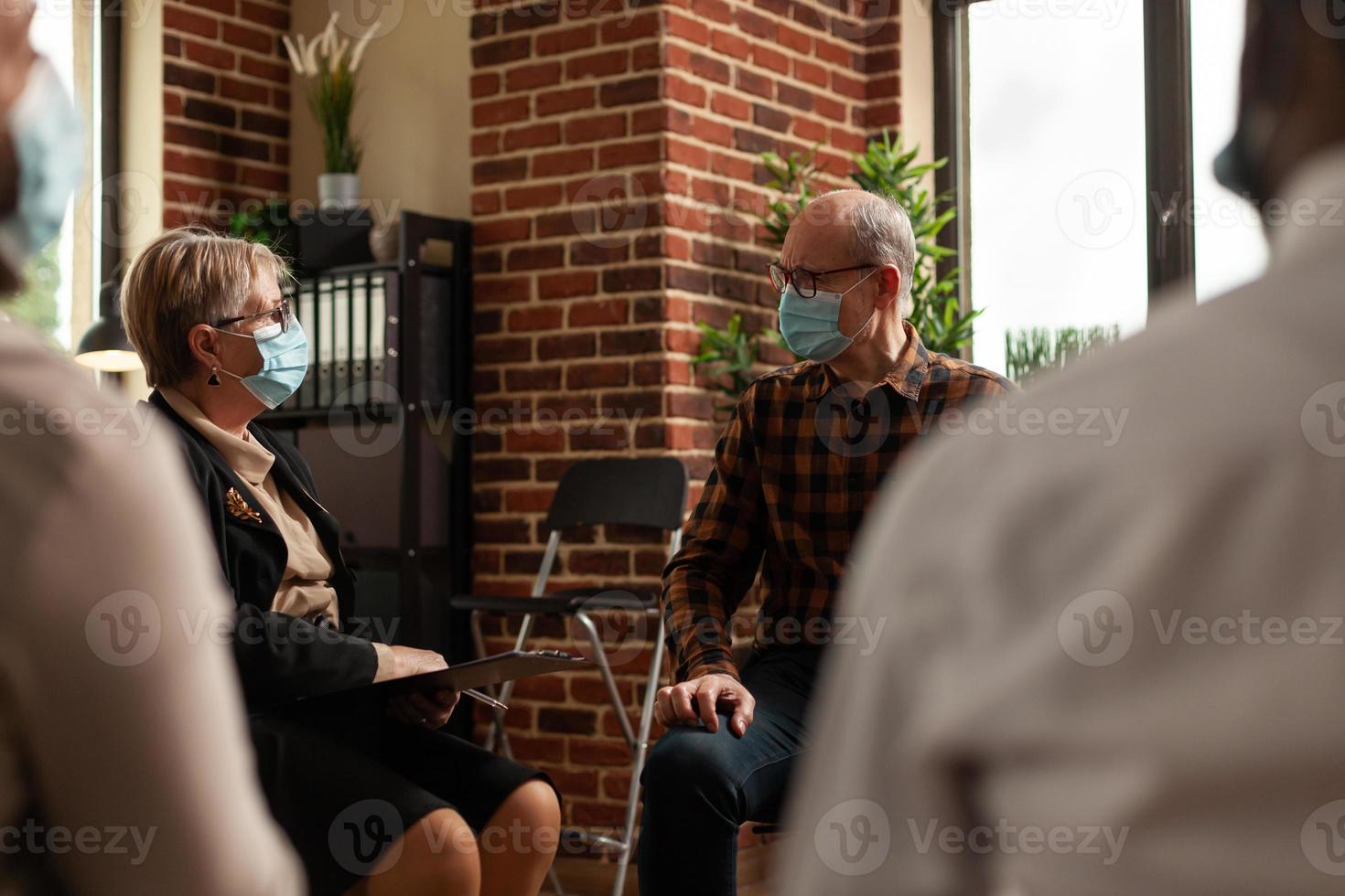 Anciano con mascarilla hablando con pacientes en círculo en una reunión foto