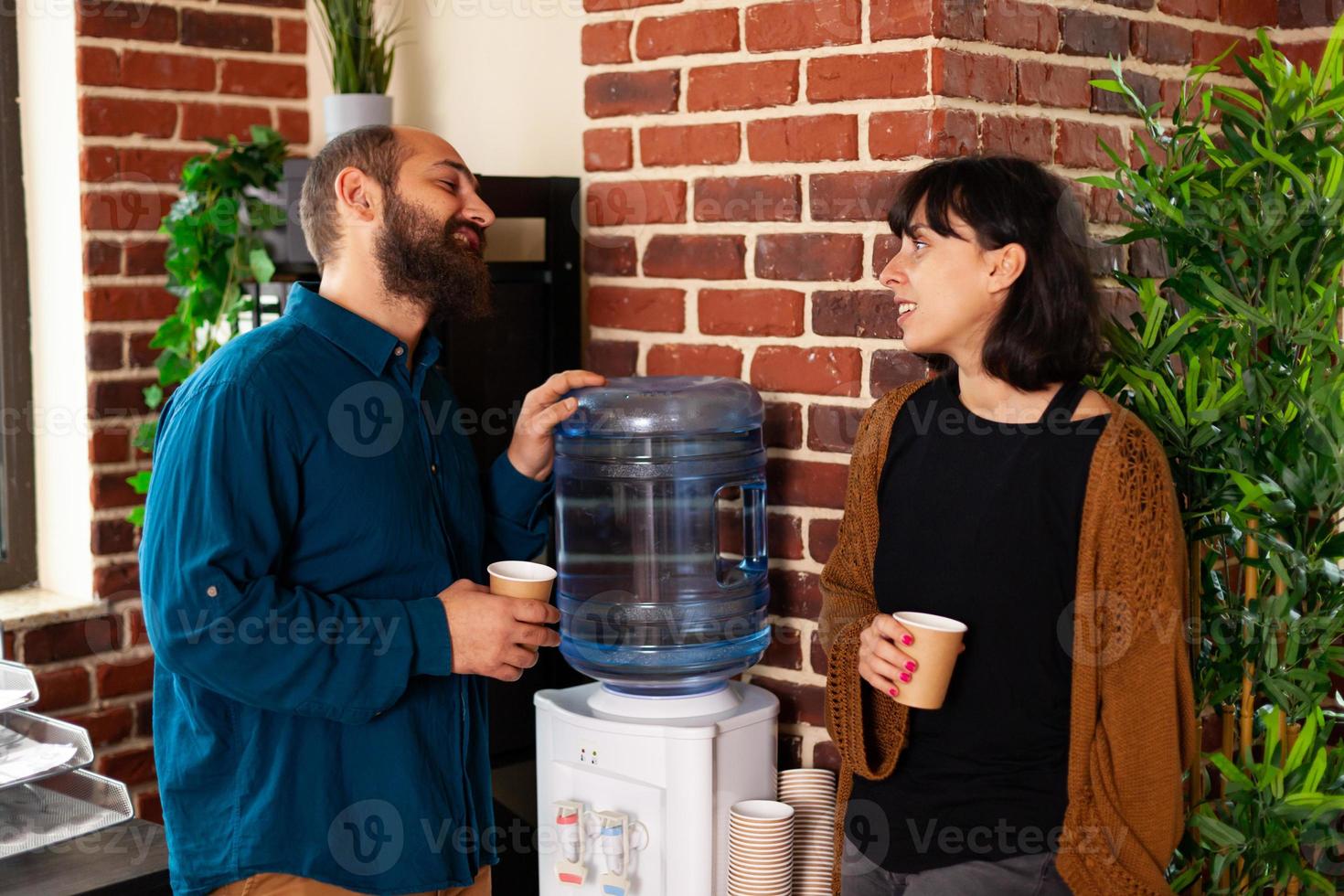 Businesspeople sitting neat to cooler dispenser discussing marketing strategy photo