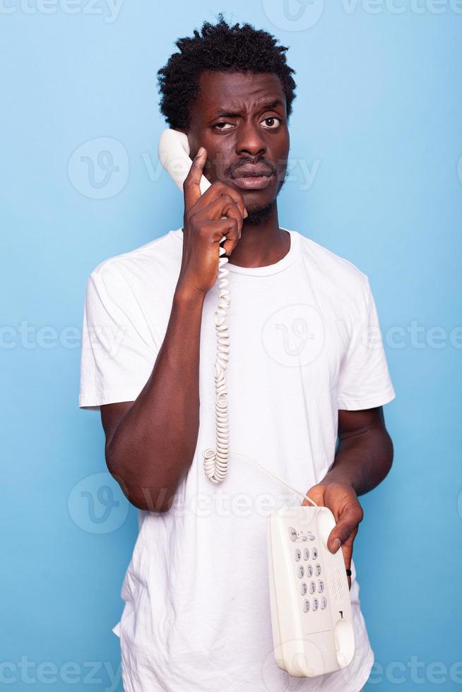 Young adult answering call on retro telephone in studio photo