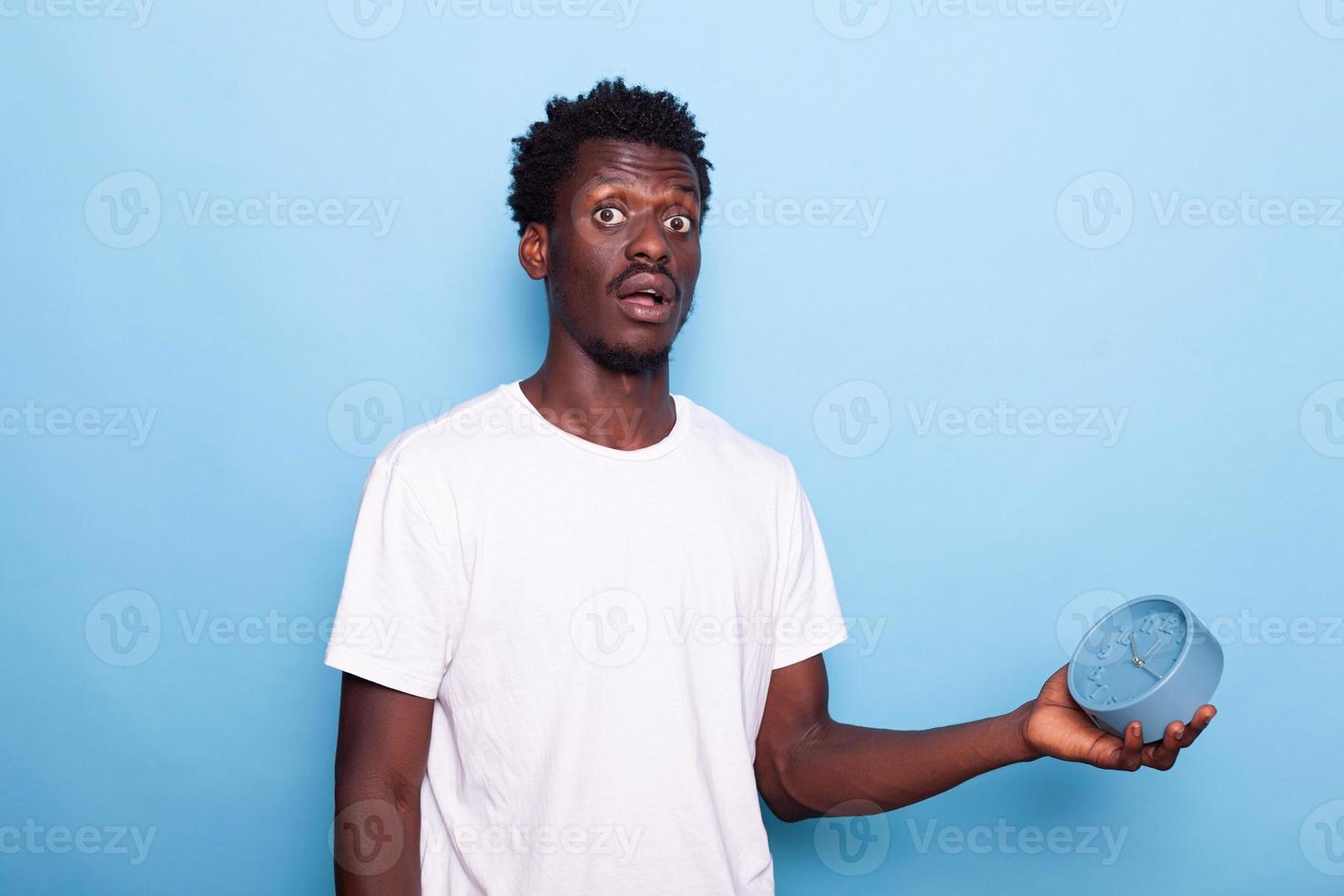 Young adult checking time on clock, being late in studio photo