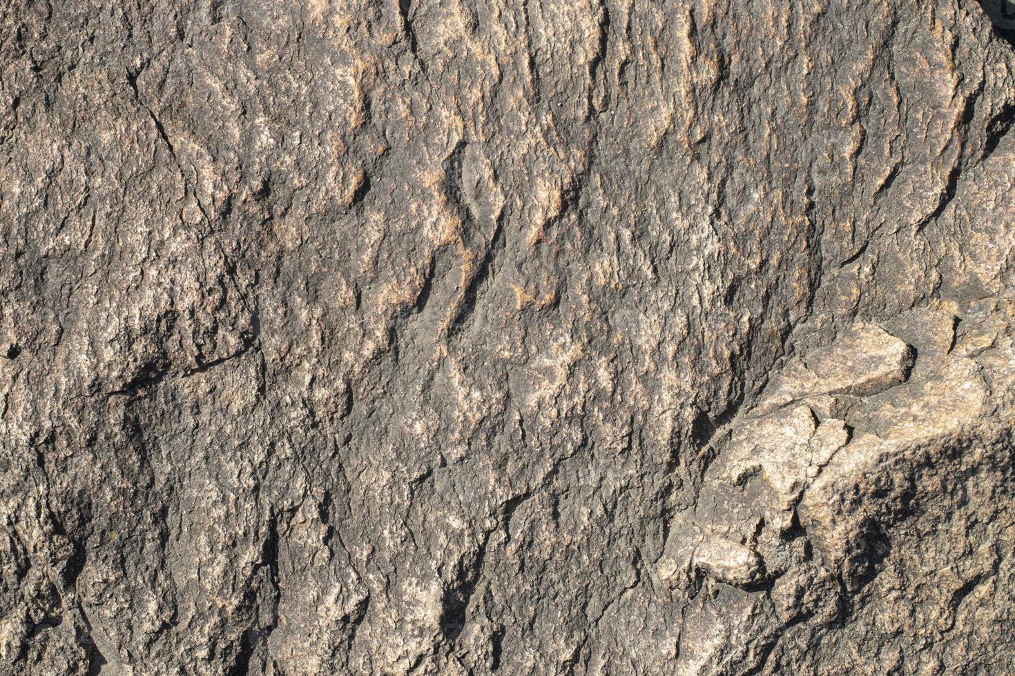 Raw gray granite rock texture background. Fragment of natural stone wall photo