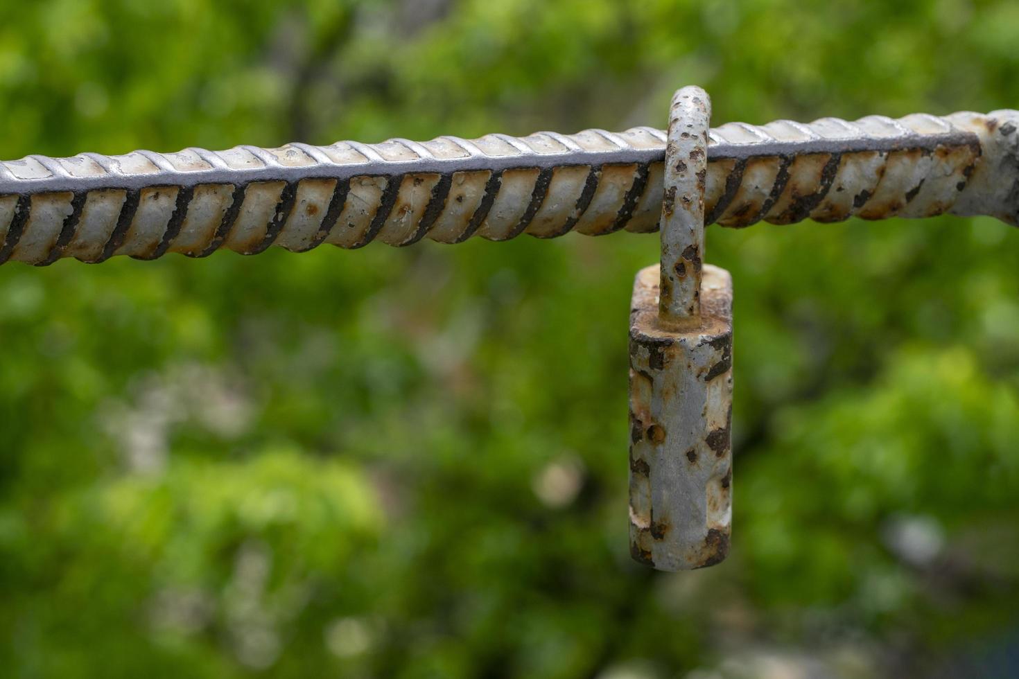 Old padlock of gray color with spots from rust. Vintage padlock on a green background photo