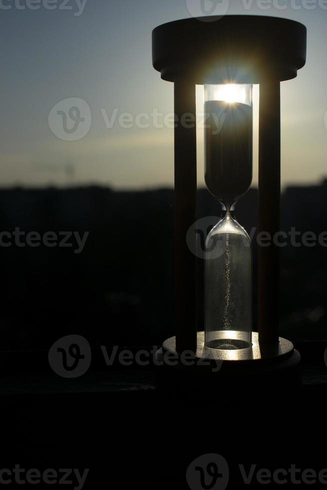 Hourglass close-up on a background of blue sky with clouds. photo