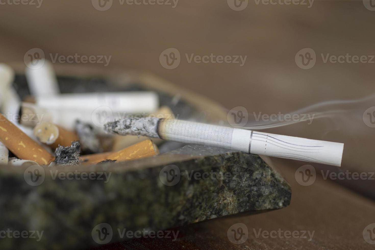 un cigarrillo humeante en un cenicero de granito. foto