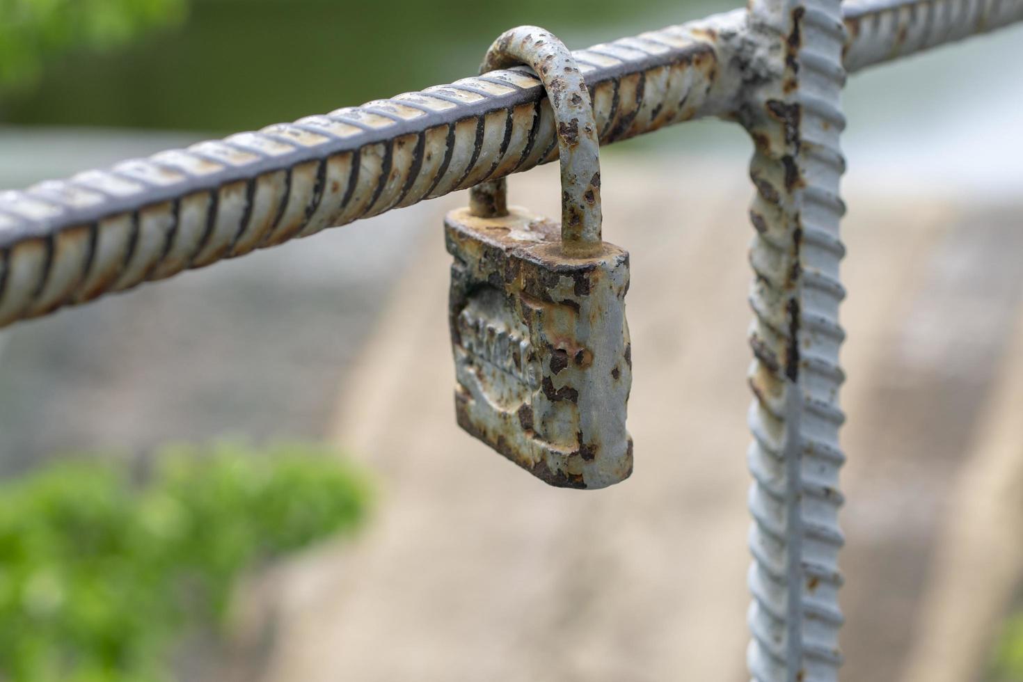 Old padlock of gray color with spots from rust. Vintage padlock on a green background.Close-up old padlock photo