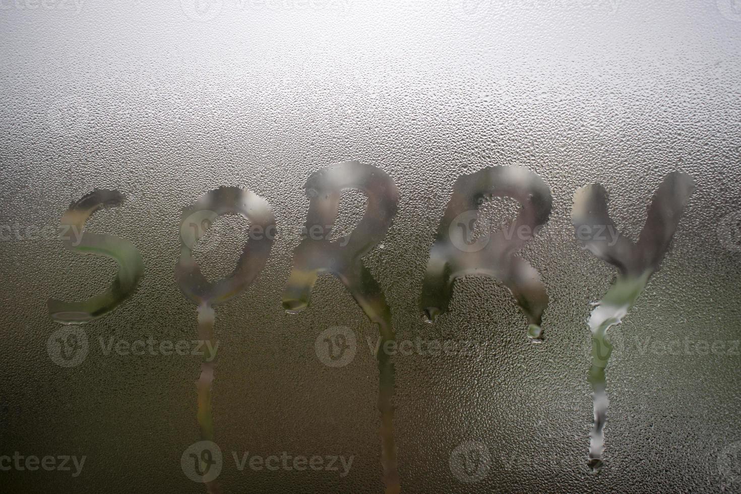 Lo siento conceptual palabra mensaje escrito a mano en la ventana de cristal lluvioso foto