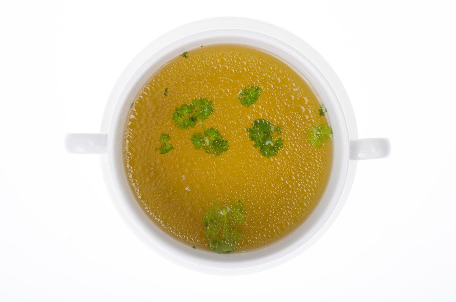 Transparent meat broth with herbs in white plate photo