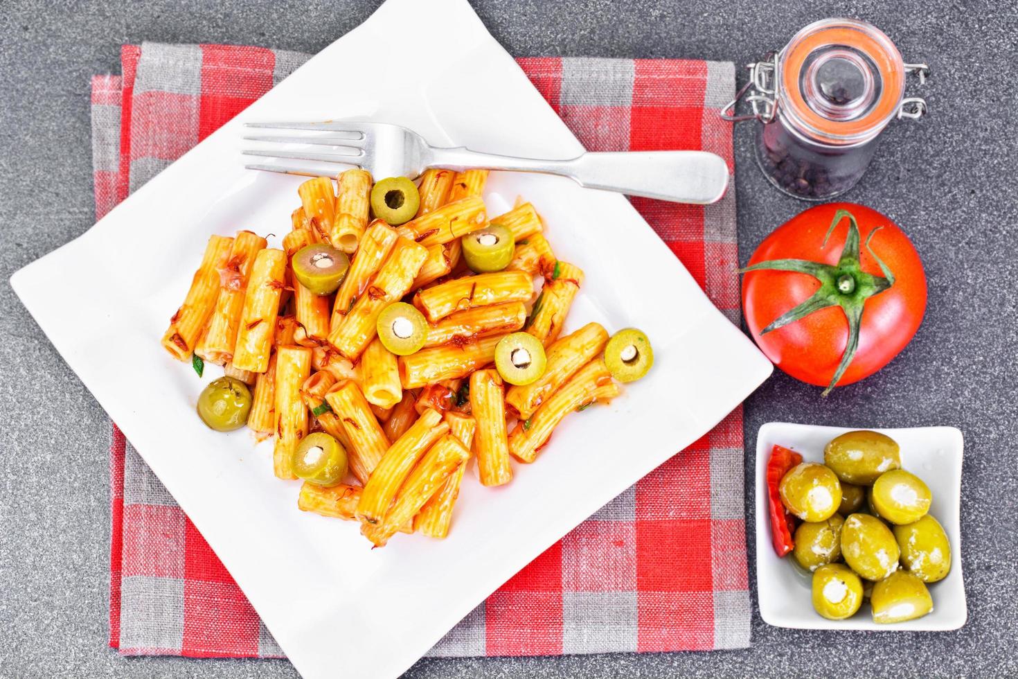 tortellini, pasna penne con salsa de tomate y aceitunas verdes foto