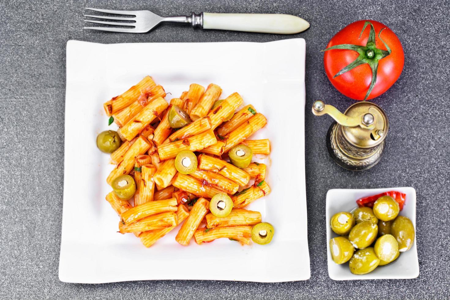 tortellini, pasna penne con salsa de tomate y aceitunas verdes foto