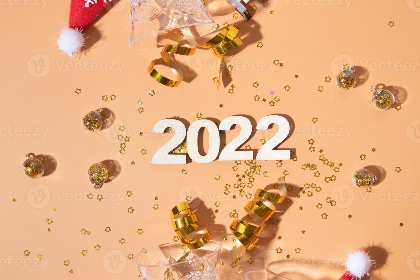 Festive new year flat lay with numbers 2022 and hard shadows with glasses and shiny decor photo