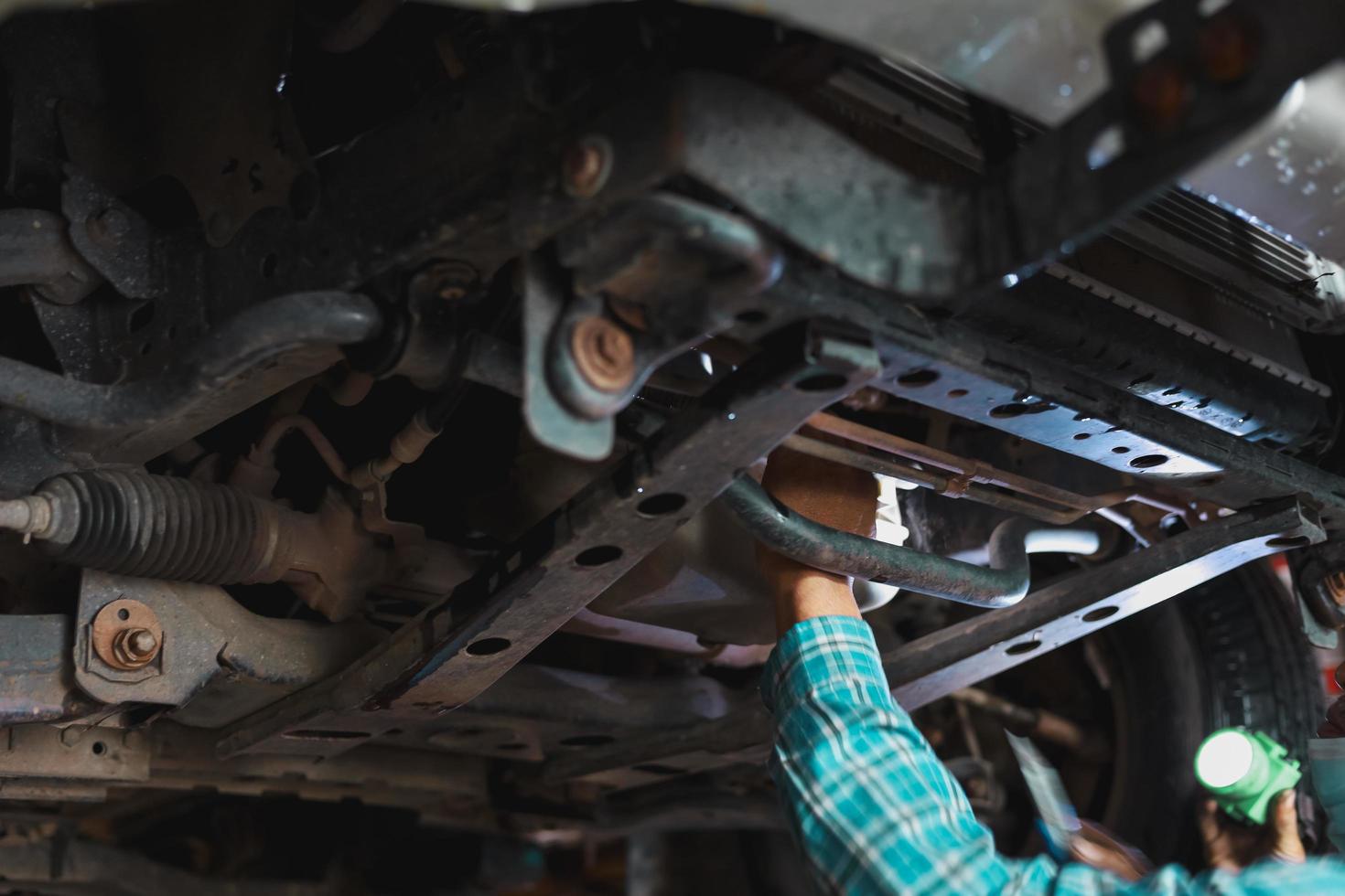 The mechanic is checking the undercarriage of the car. photo