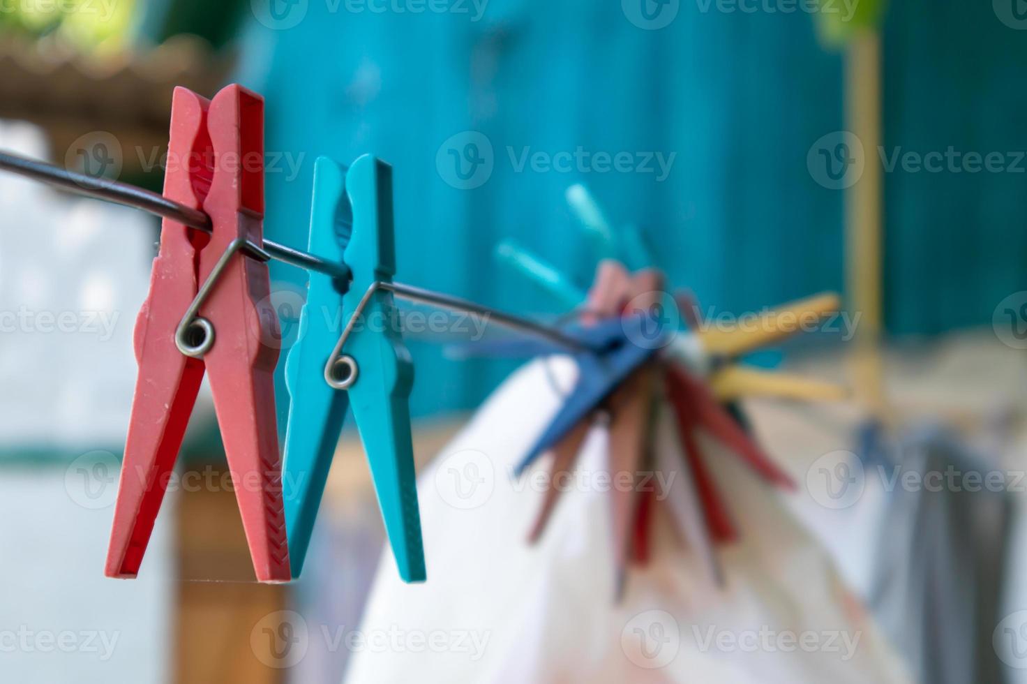 Plastic clothespins hang in a row on the rope. Rope outdoors, on a blurred background in a sunny garden. Clothesline on the street. Clothespins. photo