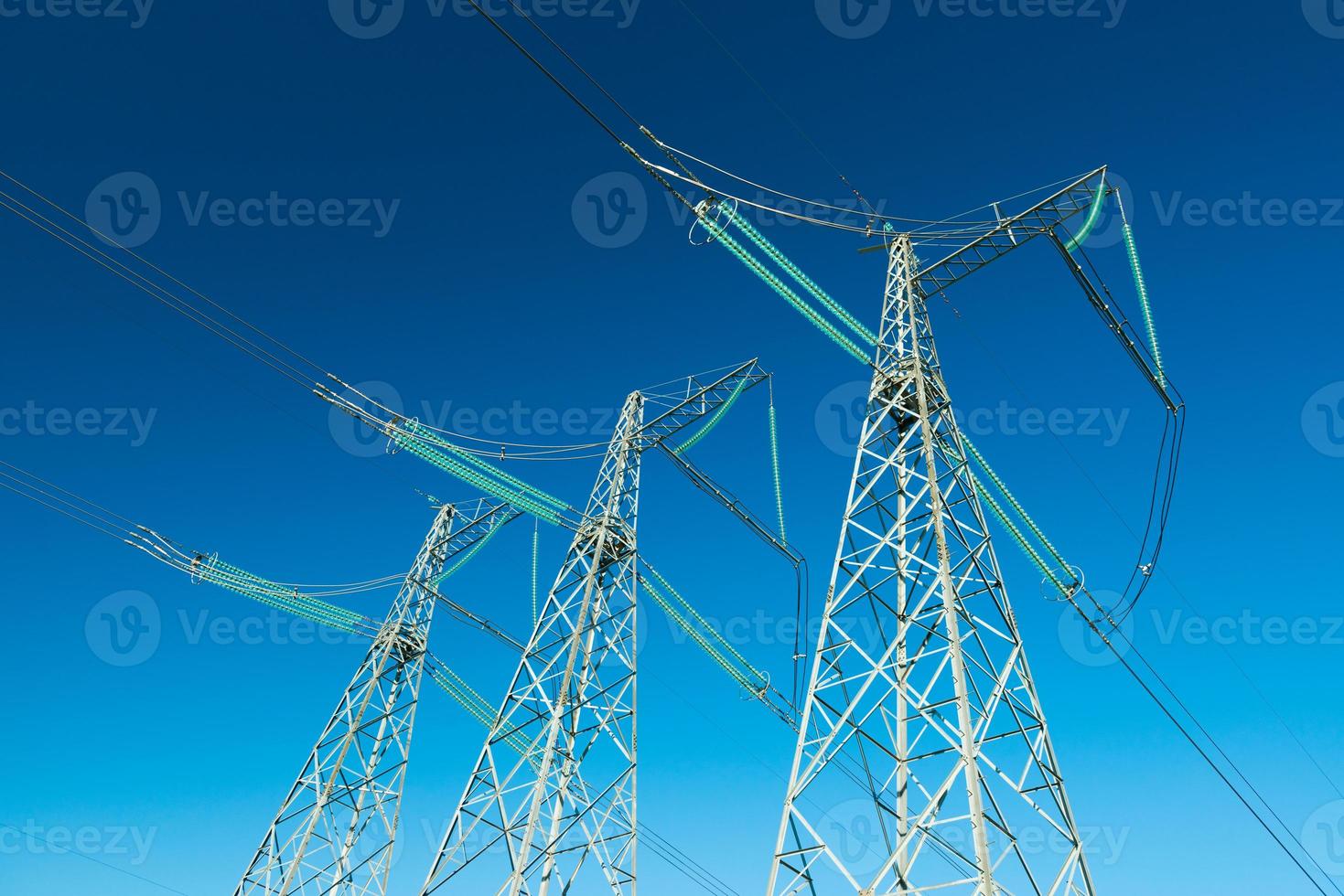 High voltage power lines with blue sky on the background, three electricity pylons photo