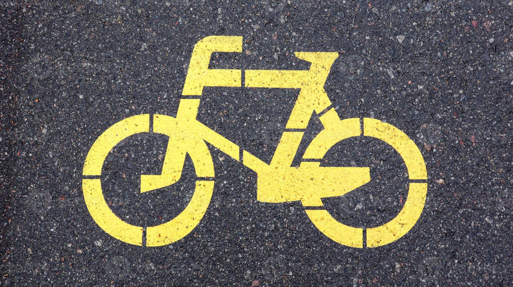 Bicycle symbol representing a path for bicycles. Yellow painted sign for bicycles on the asphalt. Flat lay, top view. photo