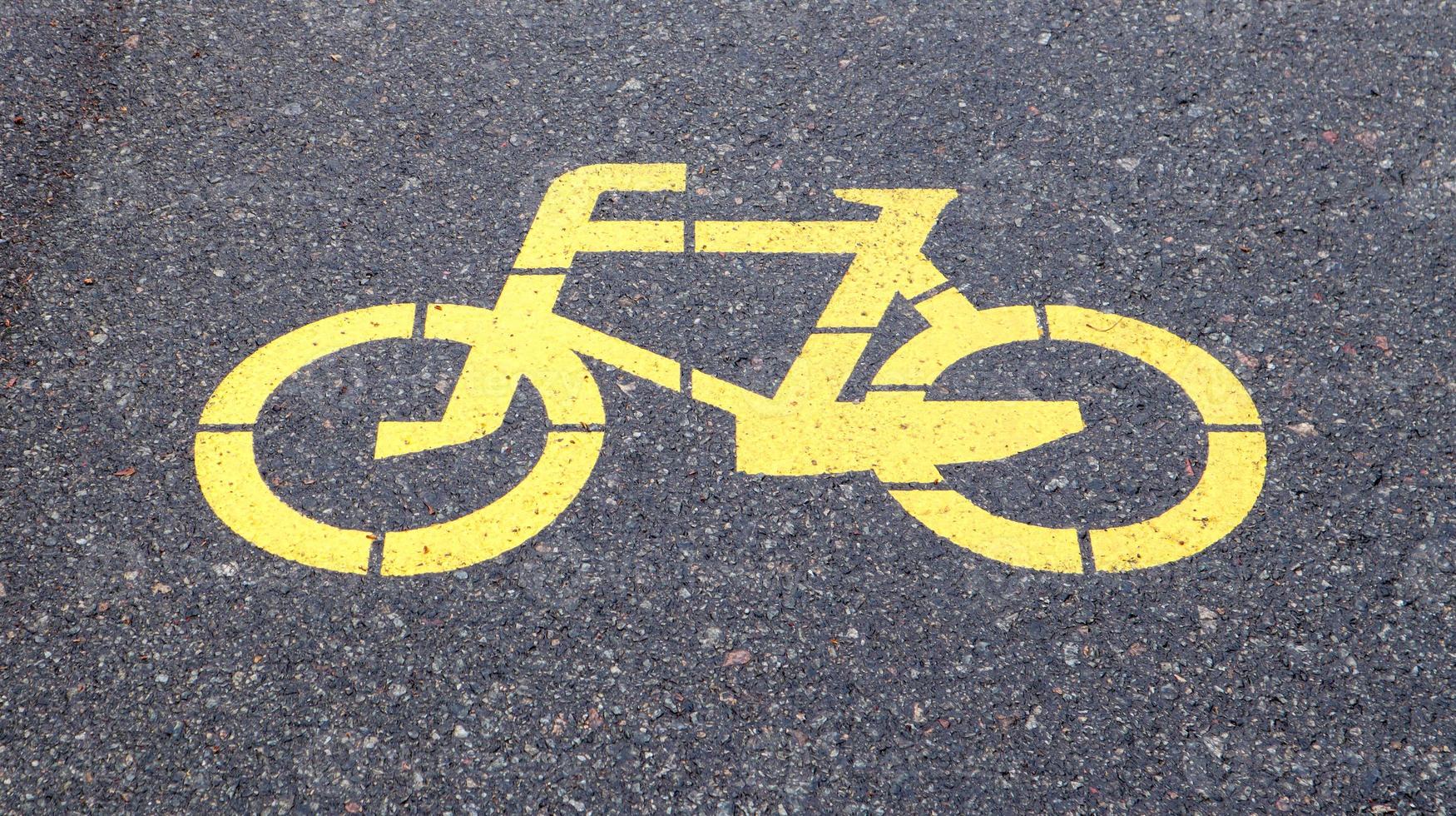 símbolo de la bicicleta que representa un camino para bicicletas. cartel pintado de amarillo para bicicletas en el asfalto. endecha plana, vista superior. foto
