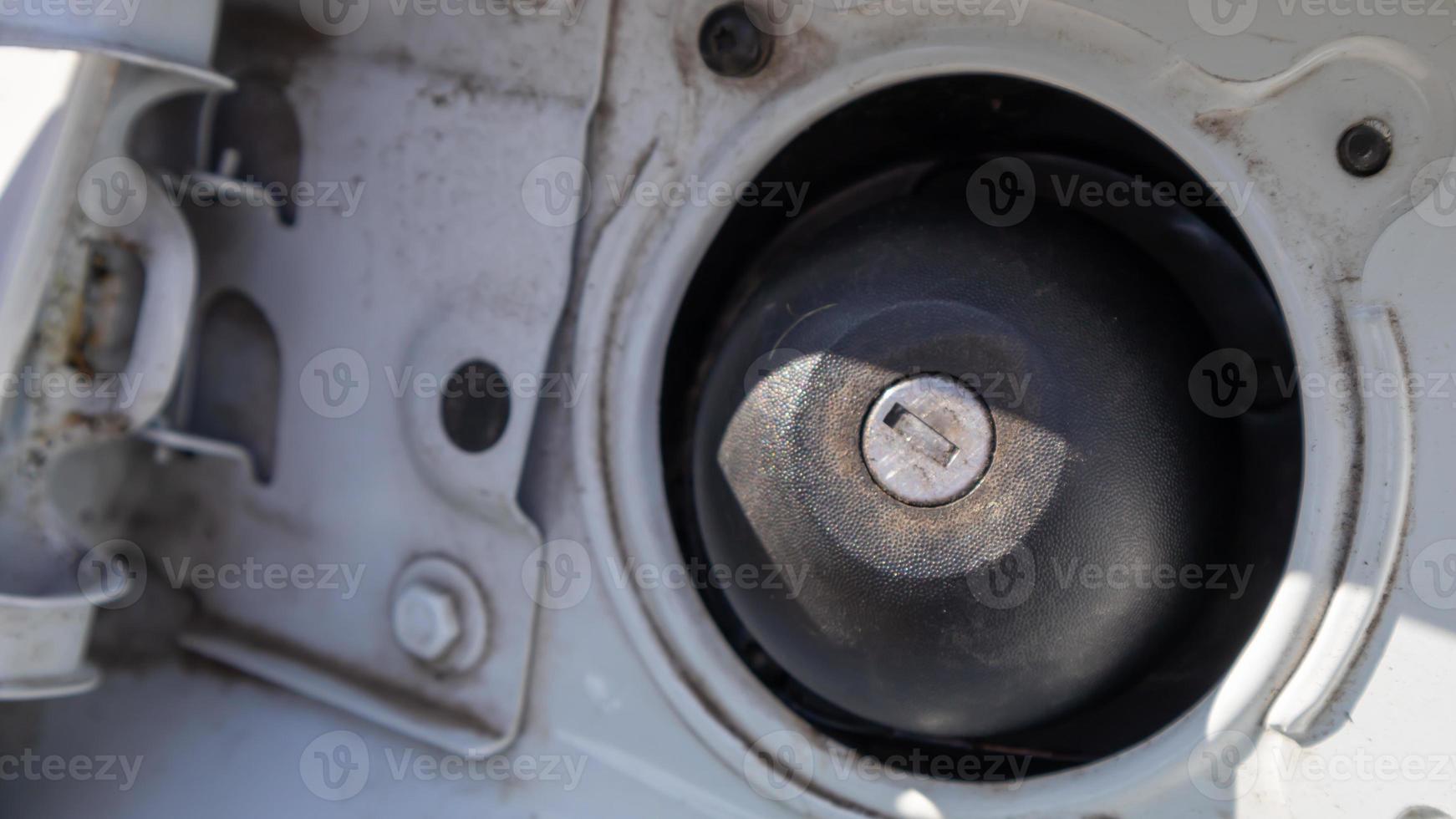 tapón de combustible de un coche deportivo blanco. cierre la tapa del tanque de gasolina. el tanque de combustible está abierto. la puerta de llenado de combustible está abierta y la tapa de llenado de combustible está cerrada. el exterior del coche con la puerta de llenado abierta. foto