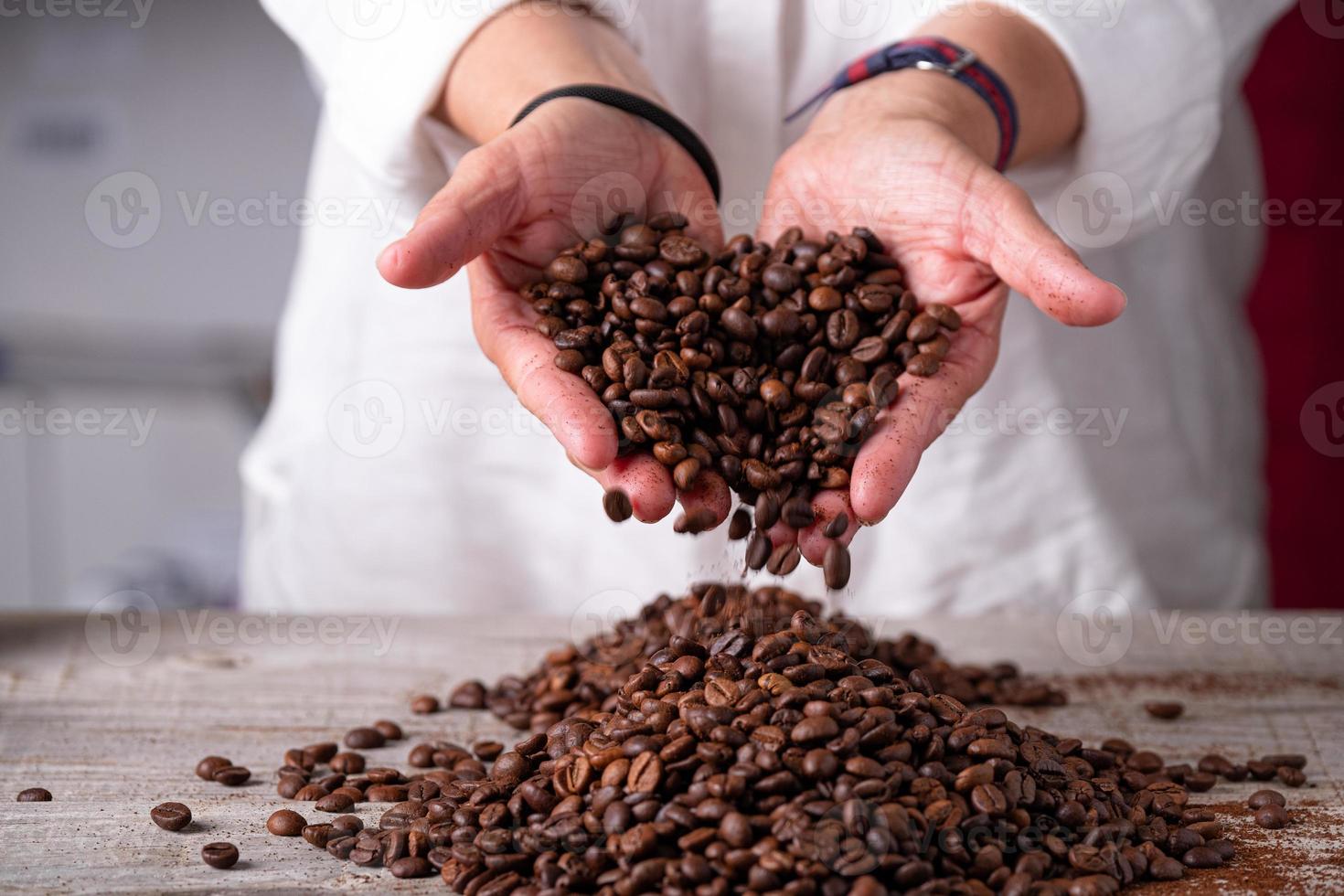 Manos de la persona que deja caer el café sobre una tabla de madera foto