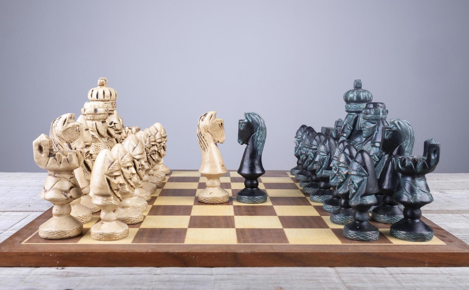 chess board with collection pieces put in order and the horses faced photo
