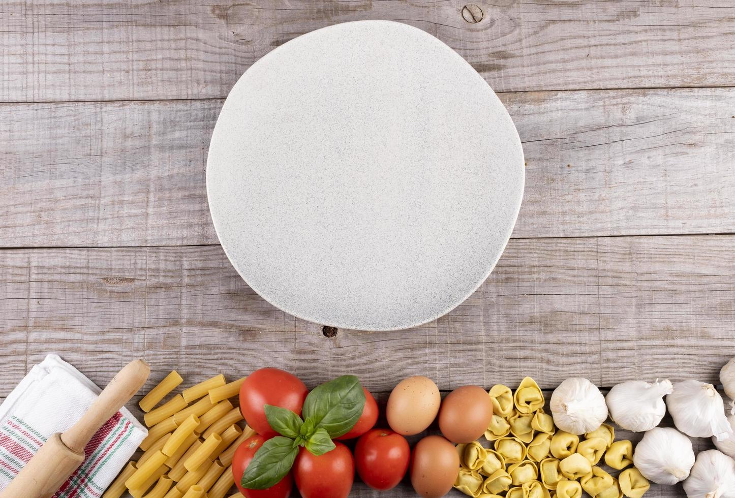 pasta, verduras, huevos, con plato en el medio sobre tabla de madera foto