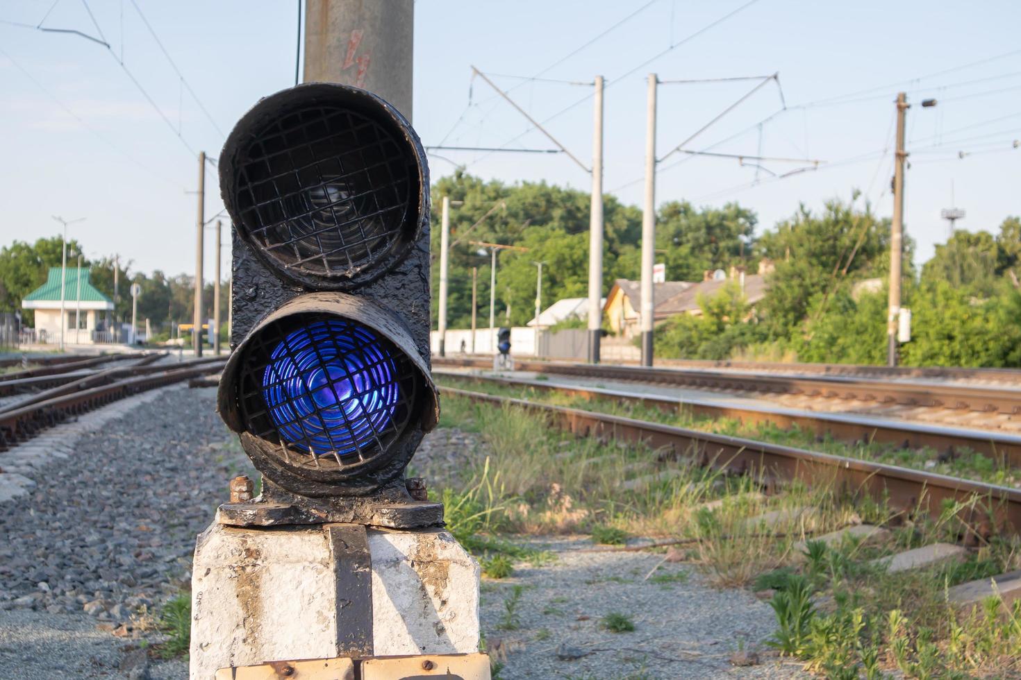 señal de ferrocarril con luz azul con un cruce de ferrocarril. tren semáforo azul que prohíbe el tráfico. cruce ferroviario. industria pesada. vias ferreas. el semáforo de la vía férrea está iluminado en azul. foto