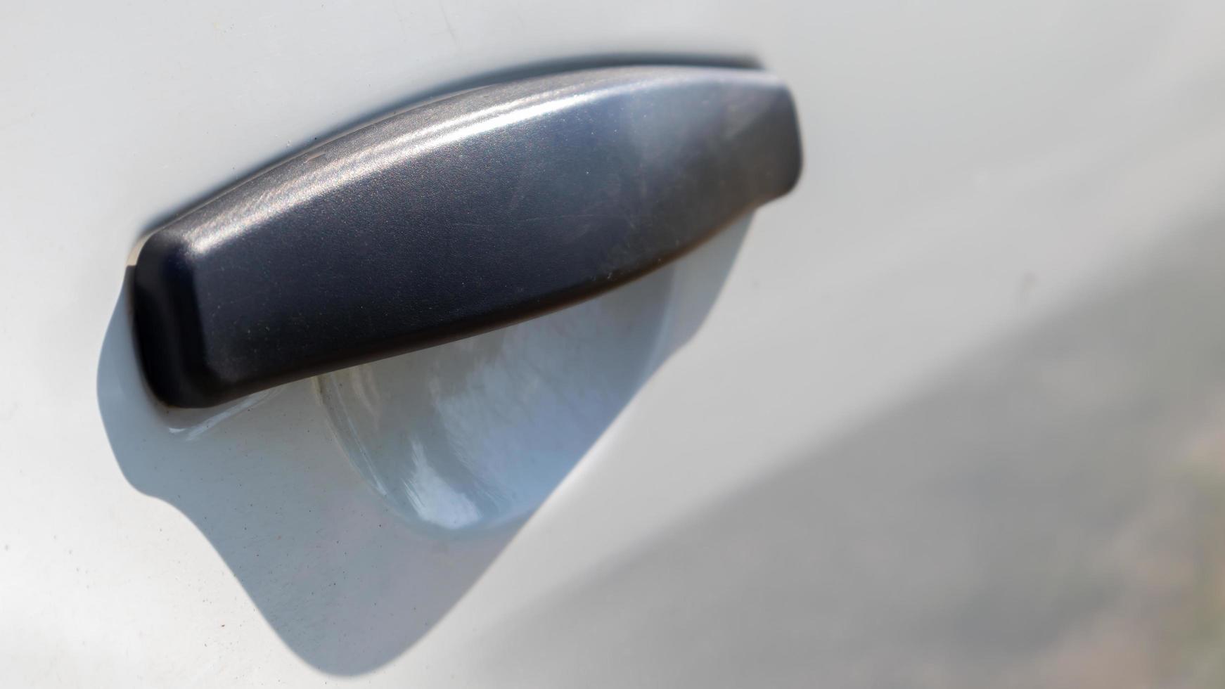 Black plastic door handle of a modern white car. Transport. Detail and part of the car. Door opening handle from outside. photo