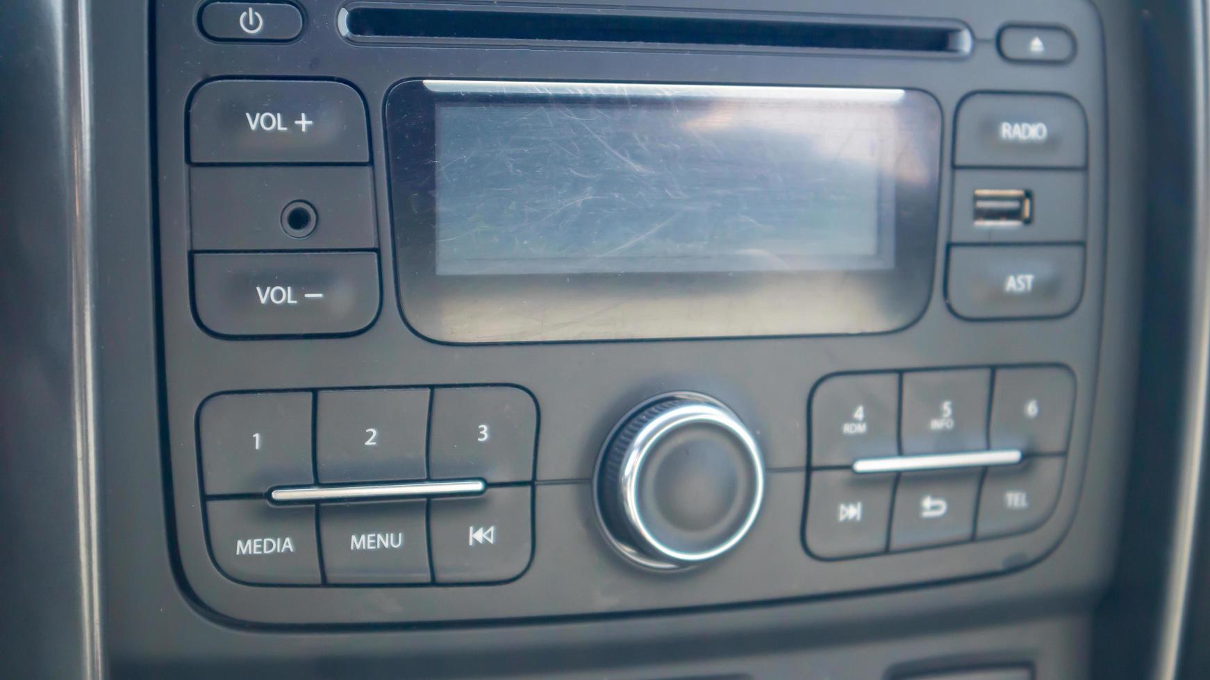 Established multimedia in the car. Close-up of the head unit and radio receiver with display inside the car. Dust and scratches are visible on the device screen. Multimedia system. photo