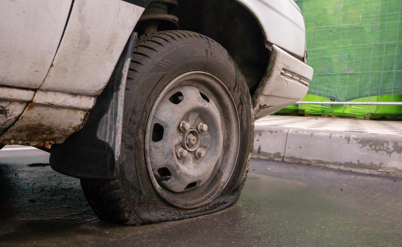 Abandoned old broken car with flat wheels. A tire with a flat tire. The concept of accident, breakdown, repair, insurance. A flat tire on a car wheel. Ukraine, Kiev - August 19, 2021. photo