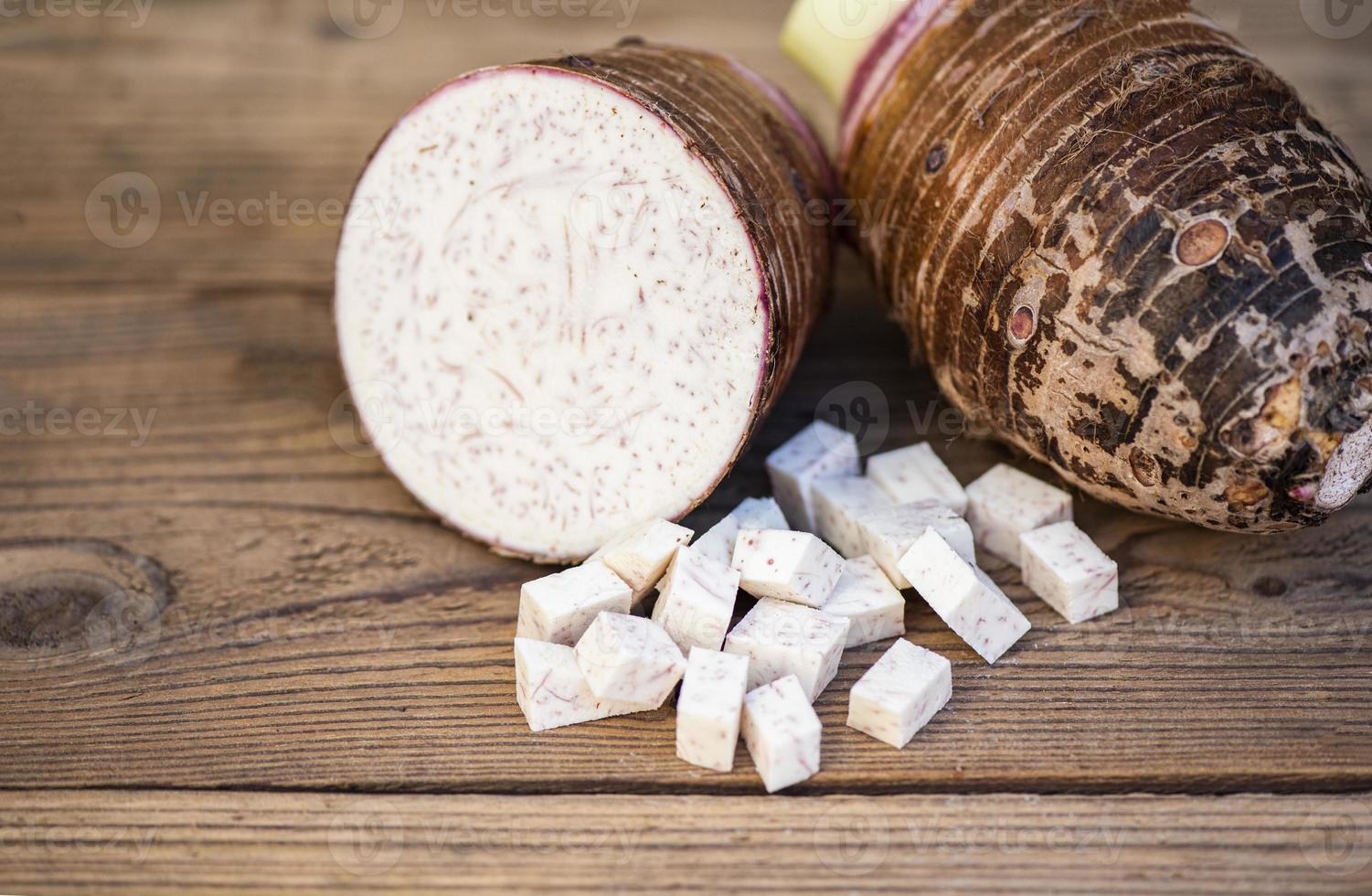 Raíz de taro con la mitad y cubos de rodajas sobre fondo de madera, raíz de taro orgánico crudo fresco listo para cocinar foto