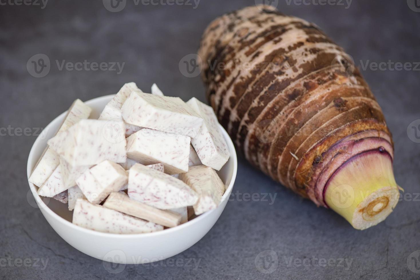 Taro root with slice cubes on bowl and dark background, Fresh raw organic taro root ready to cook photo