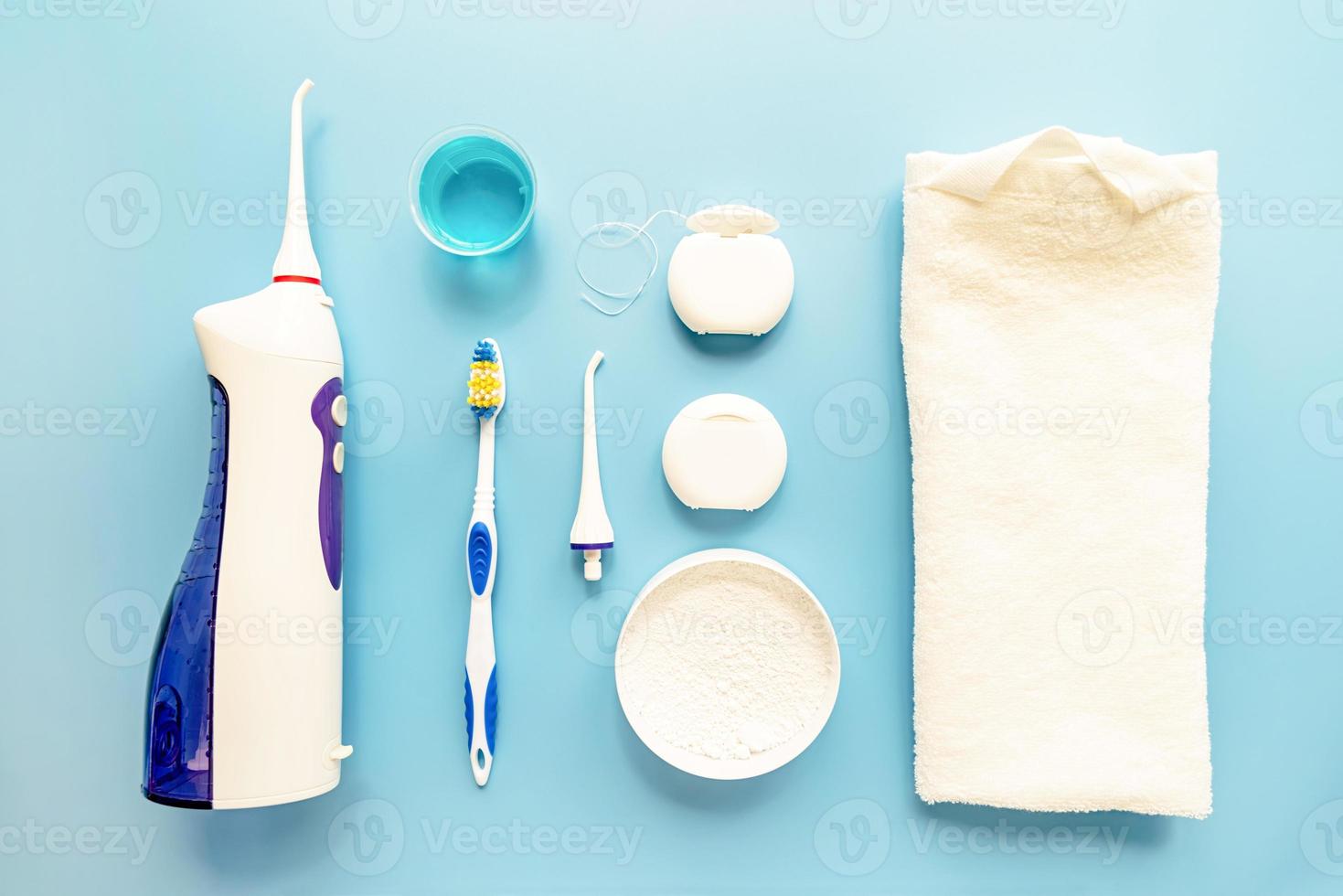 Dental tools, floss, mouth irrigator, toothbrushes and tooth powder top view on blue background photo