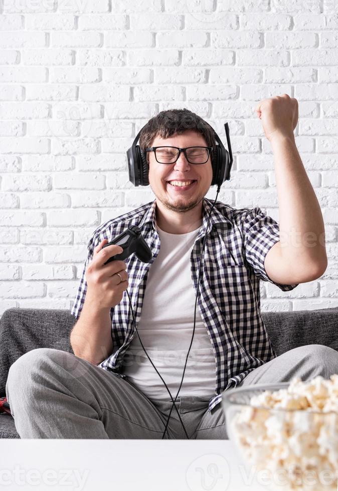 Excited young man playing video games at home enjoying his victory photo